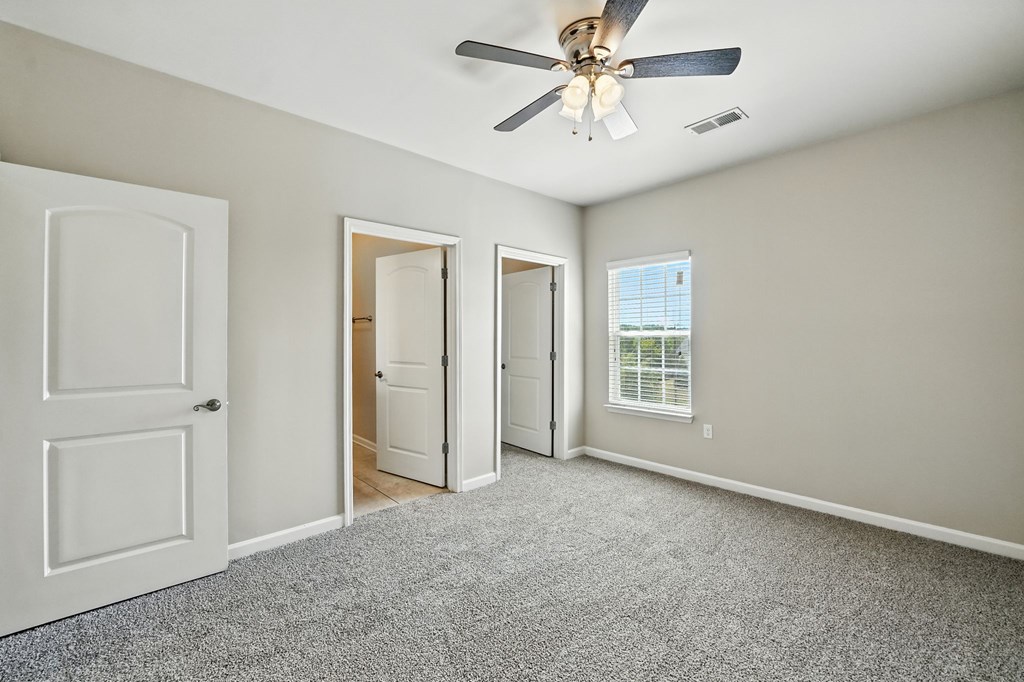 A room with a ceiling fan and carpeted floor.