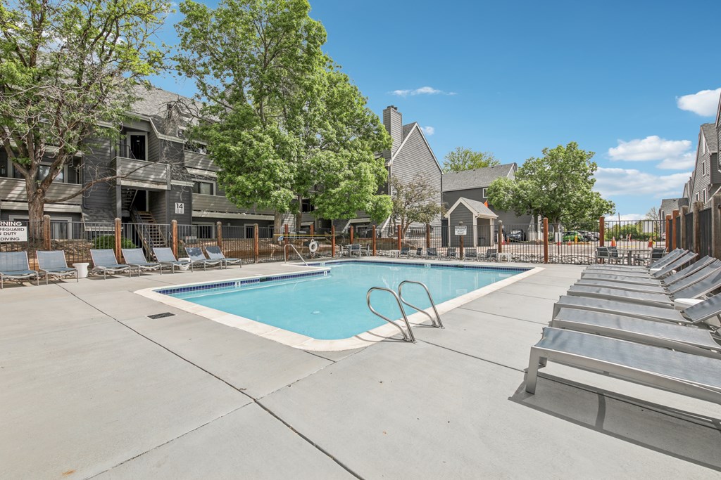 A swimming pool surrounded by lounge chairs and trees.