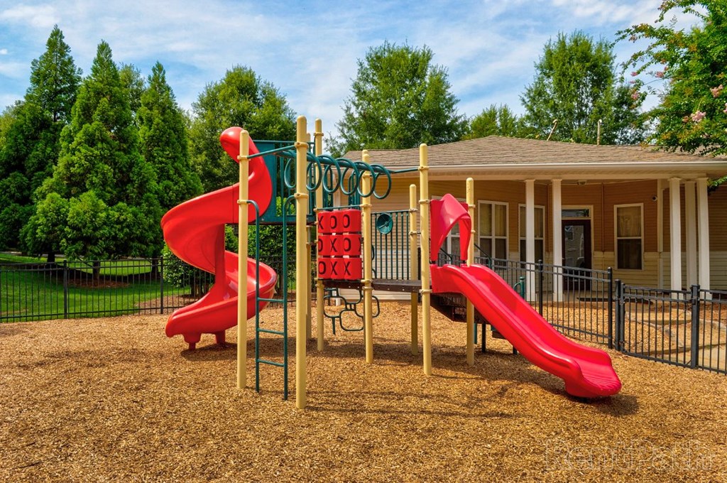 a playground with two slides in front of a house