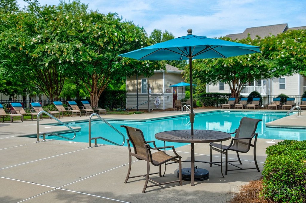 our apartments have a pool and patio with chairs and umbrella