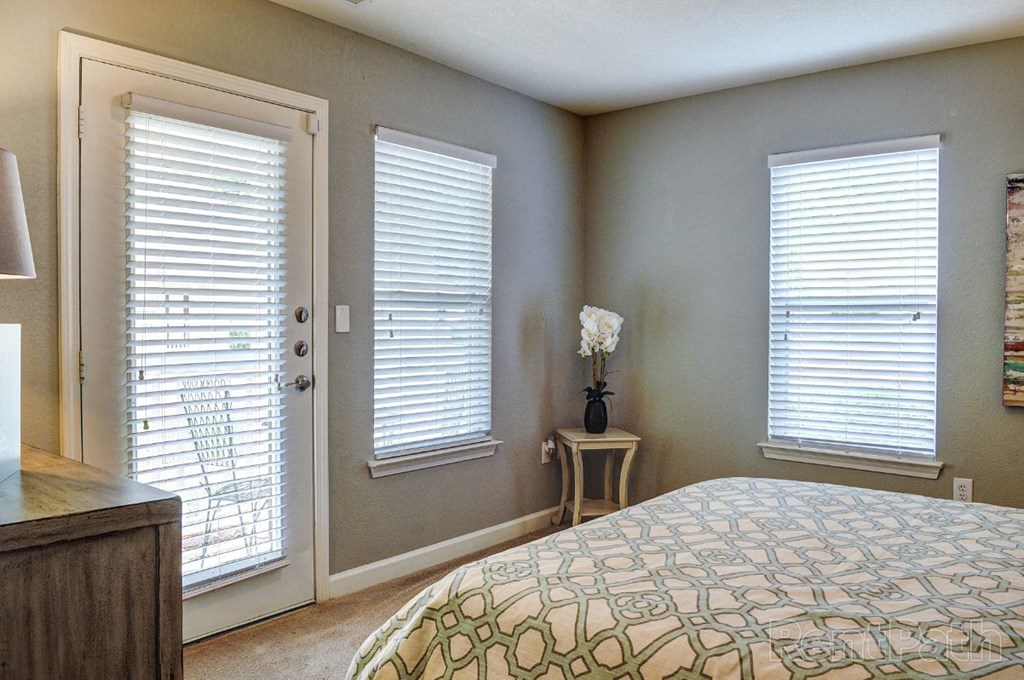 a bedroom with a bed and two windows and a door