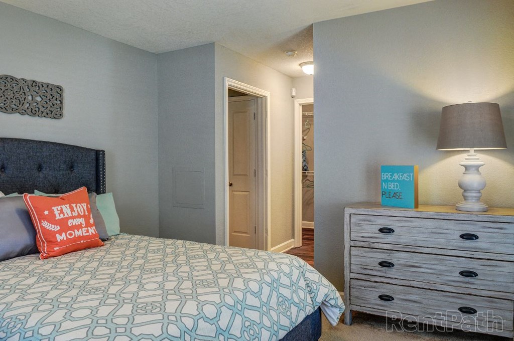 a bedroom with a bed and a dresser with a lamp