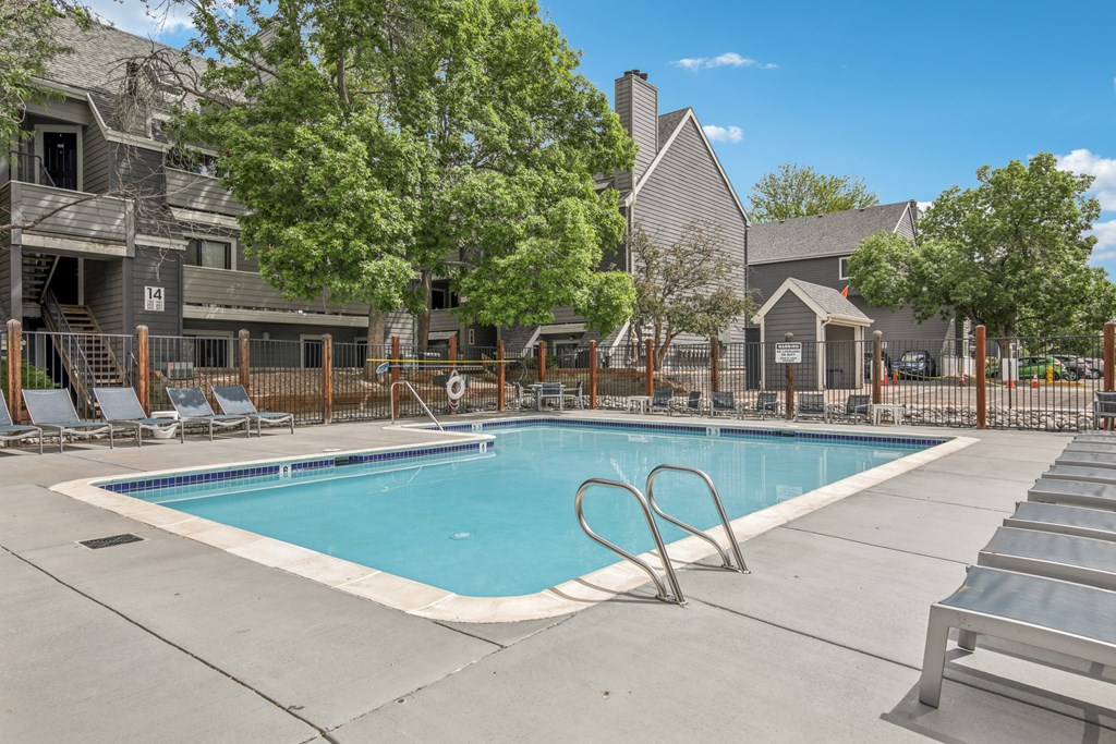 A swimming pool surrounded by lounge chairs and trees.