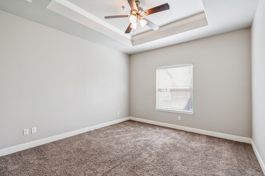 an empty room with carpet and a ceiling fan