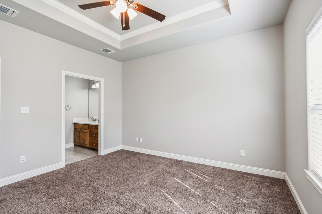 an empty living room with carpet and a ceiling fan