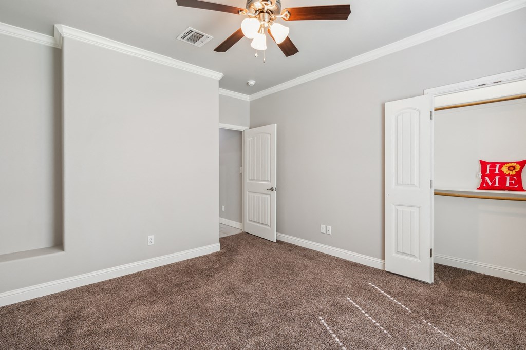 a room with carpet and a ceiling fan and a door