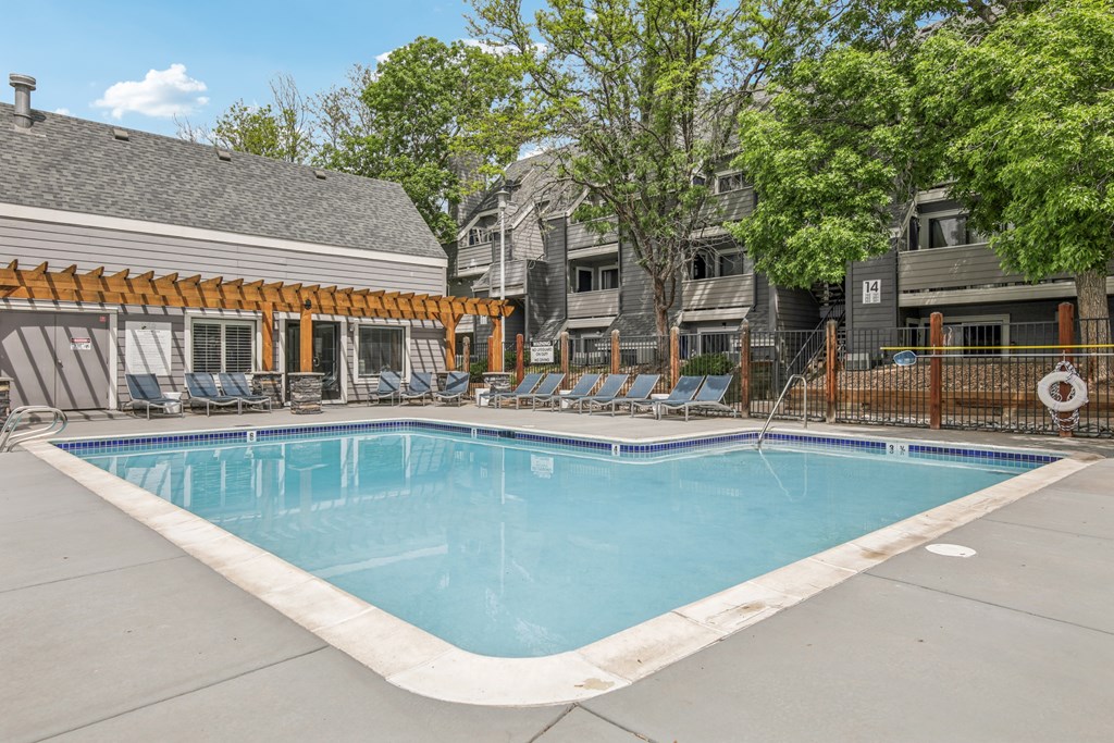 A swimming pool surrounded by lounge chairs and trees.