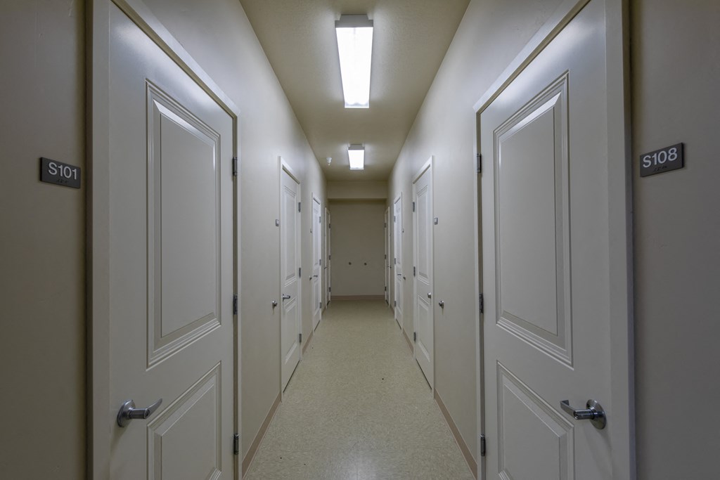 A long hallway with doors on both sides and a light on the ceiling.