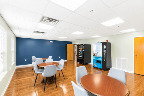 A conference room with a table, chairs, and a vending machine.