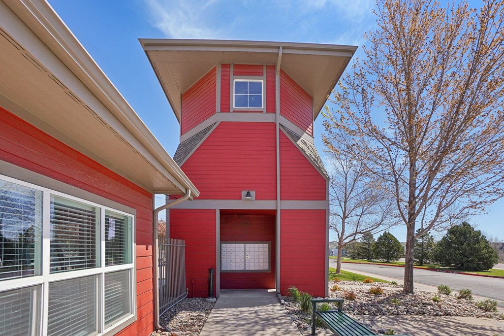 A red house with a white roof and a green bench in front. at Stetson Meadows Apartments, Colorado Springs