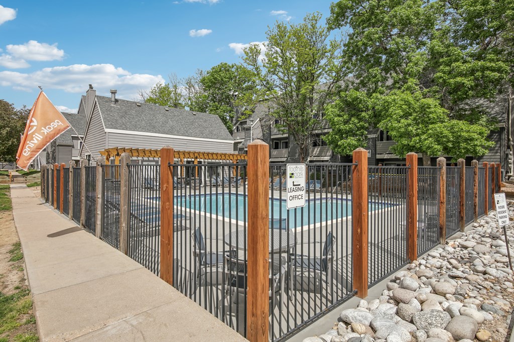 A pool surrounded by a black fence with a sign that says "SAFETY FIRST" on it.