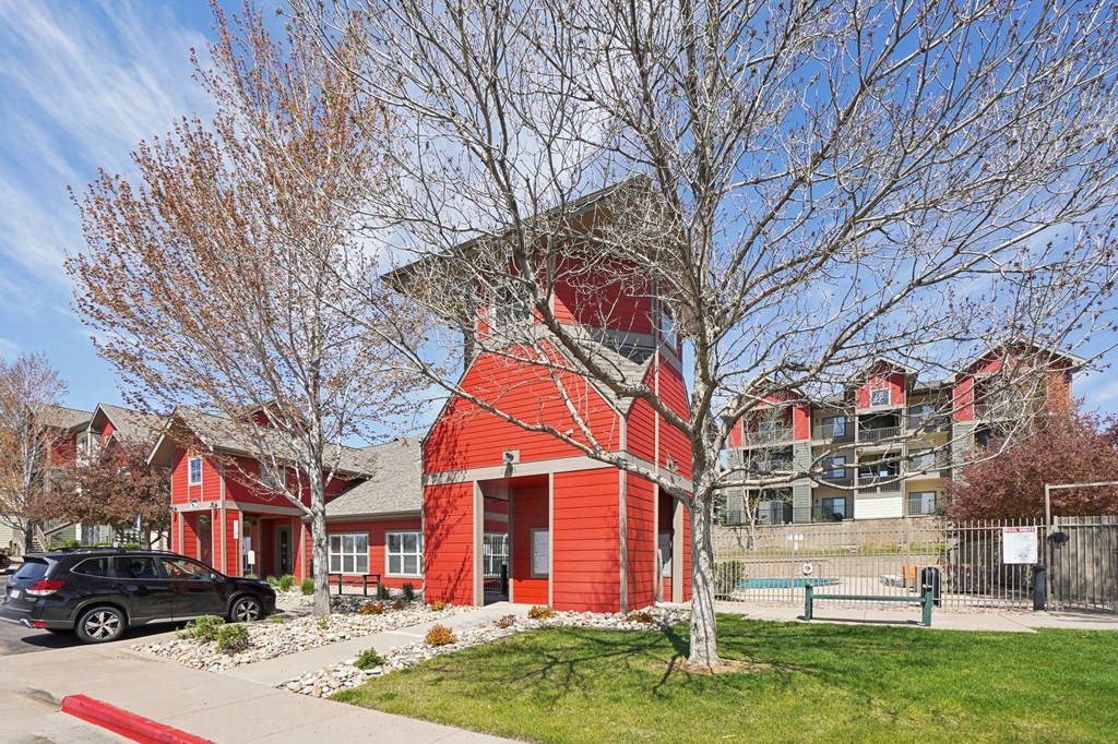 A red building with a black car parked in front. at Stetson Meadows Apartments, Colorado Springs, 80922