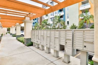 a row of mailboxes on a sidewalk with an apartment building in the background