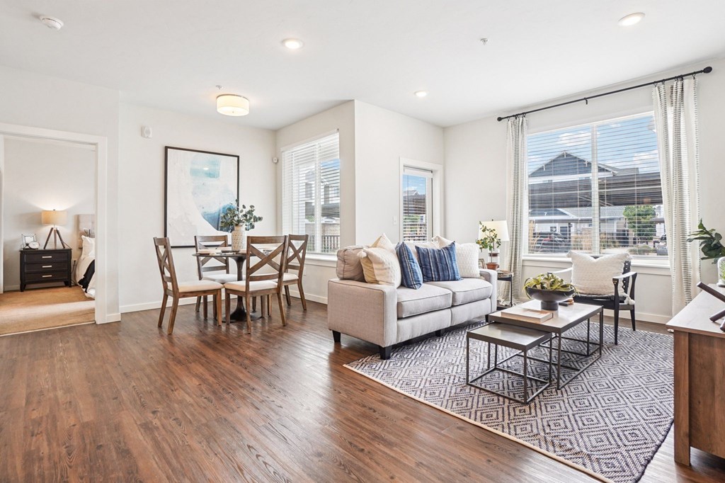 A living room with a white couch, a coffee table, and a dining table with chairs. at Connect at First Creek Apartments, Denver