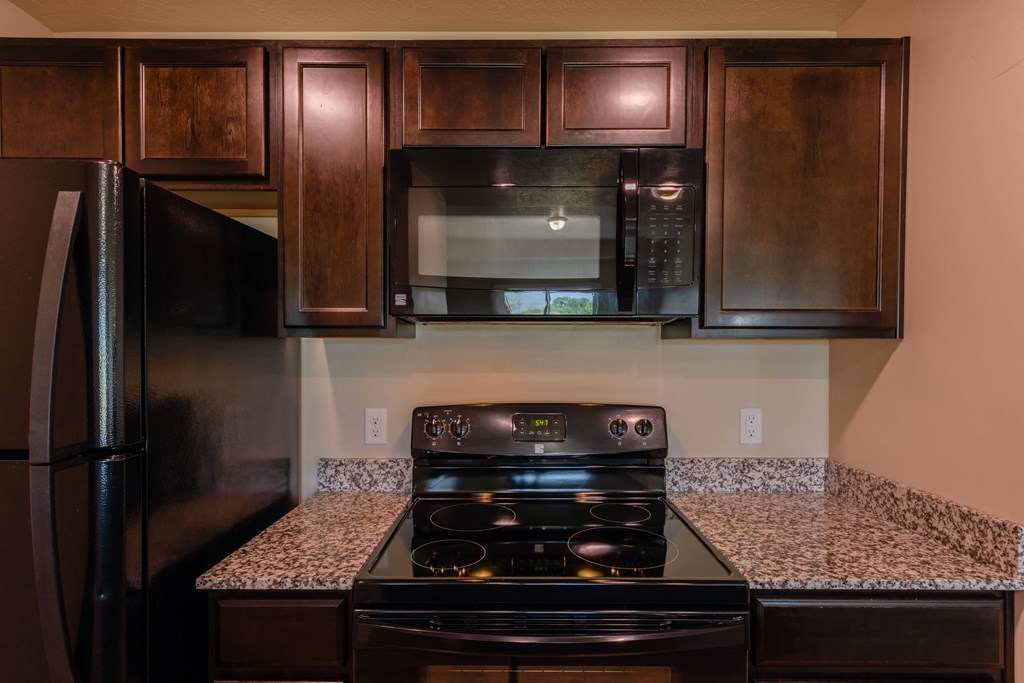 A black stove top oven with a black microwave above it.