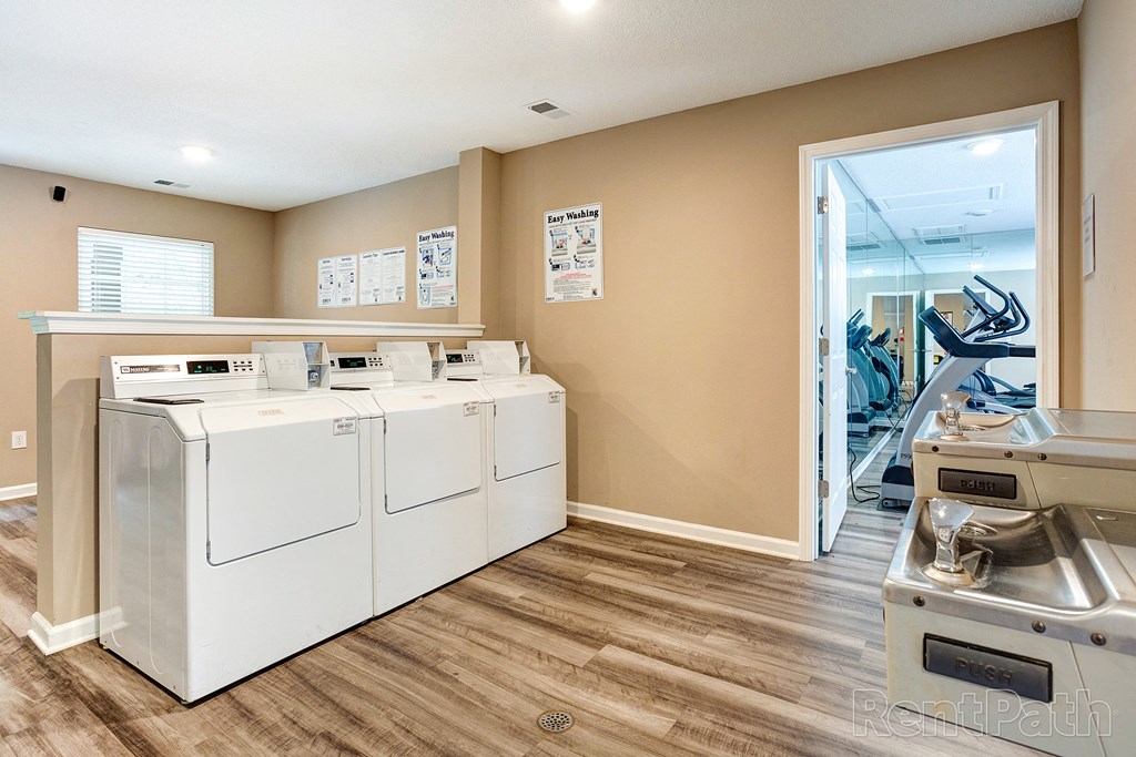 a laundry room with washers and dryers and a door to a gym