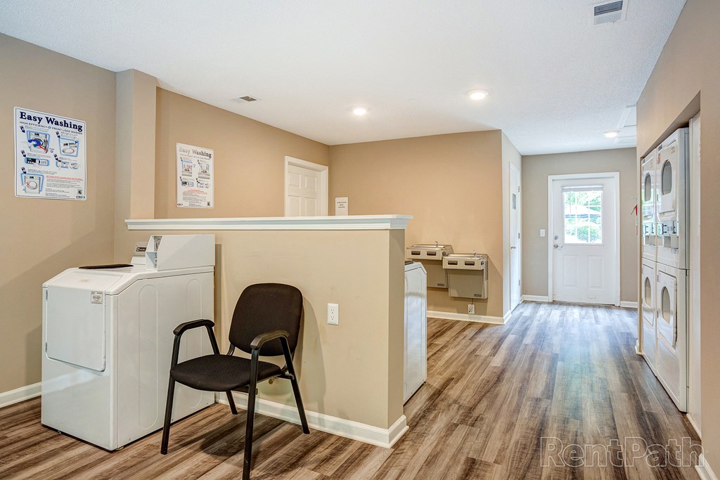a laundry room with a washer and dryer and a chair