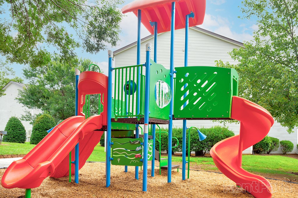 a playground with a slide and other toys in front of a house