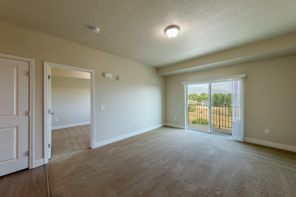 A spacious room with a carpeted floor and sliding glass doors leading to a backyard.