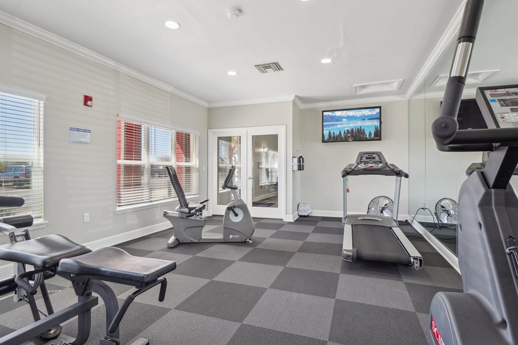 A gym with a variety of equipment including treadmills, stationary bikes, and weight machines. at Stetson Meadows Apartments, Colorado Springs