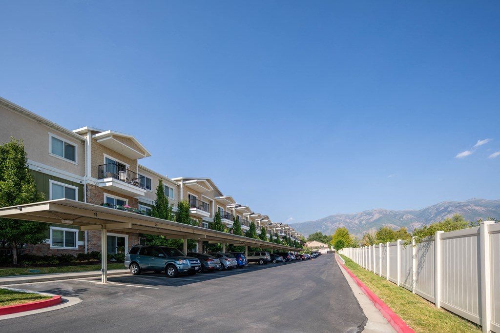 A row of townhouses with cars parked in front.