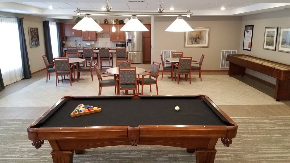 a game room with a pool table and a dining area with a bar