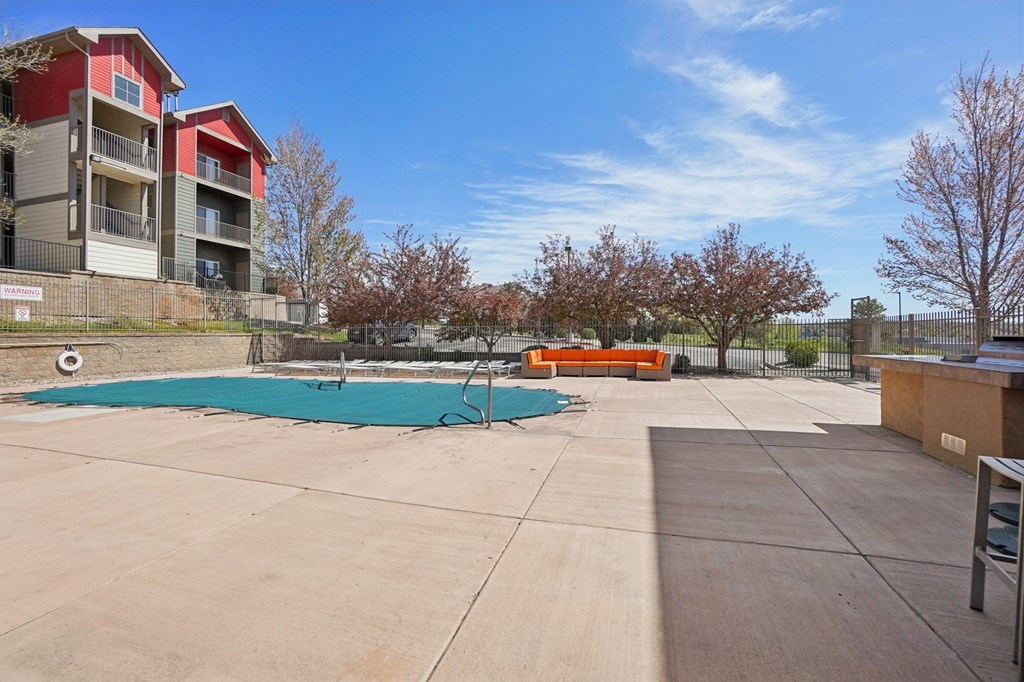 A swimming pool surrounded by a concrete patio and apartment buildings. at Stetson Meadows Apartments, Colorado Springs, CO, 80922