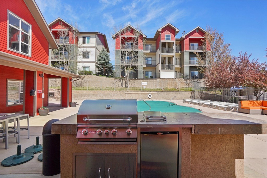 A red and white building with a pool table and a grill in front. at Stetson Meadows Apartments, Colorado, 80922