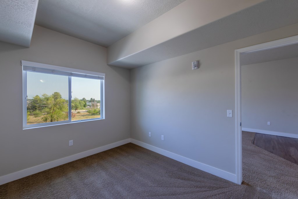 A room with a window and carpeted floor.