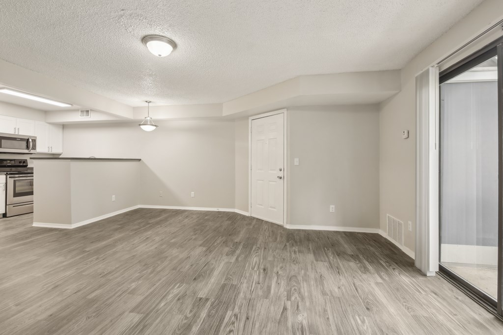 A spacious room with wooden flooring and white walls.