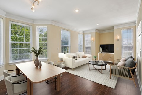 A well-lit living room with a wooden table and chairs.