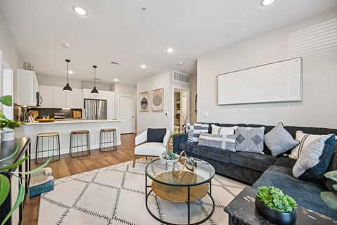 A modern living room with a grey couch and a glass coffee table.