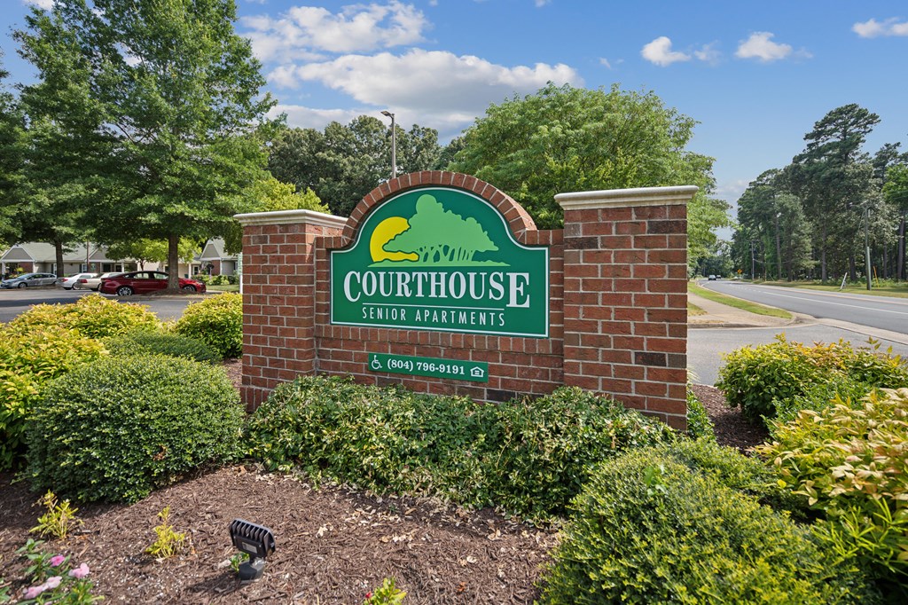 A sign for Courthouse Senior Apartments is displayed in front of a landscaped area.