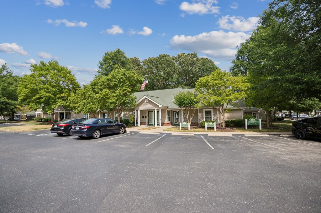 A parking lot with a building and trees in the background.