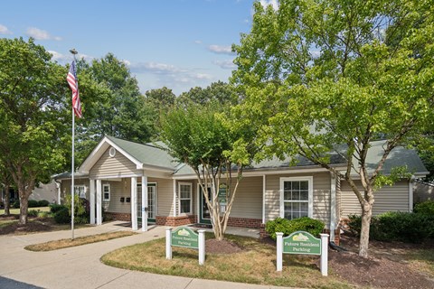 the exterior of a tan house with an flag and trees