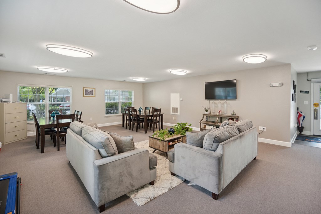 A living room with grey couches and a flat screen TV mounted on the wall.