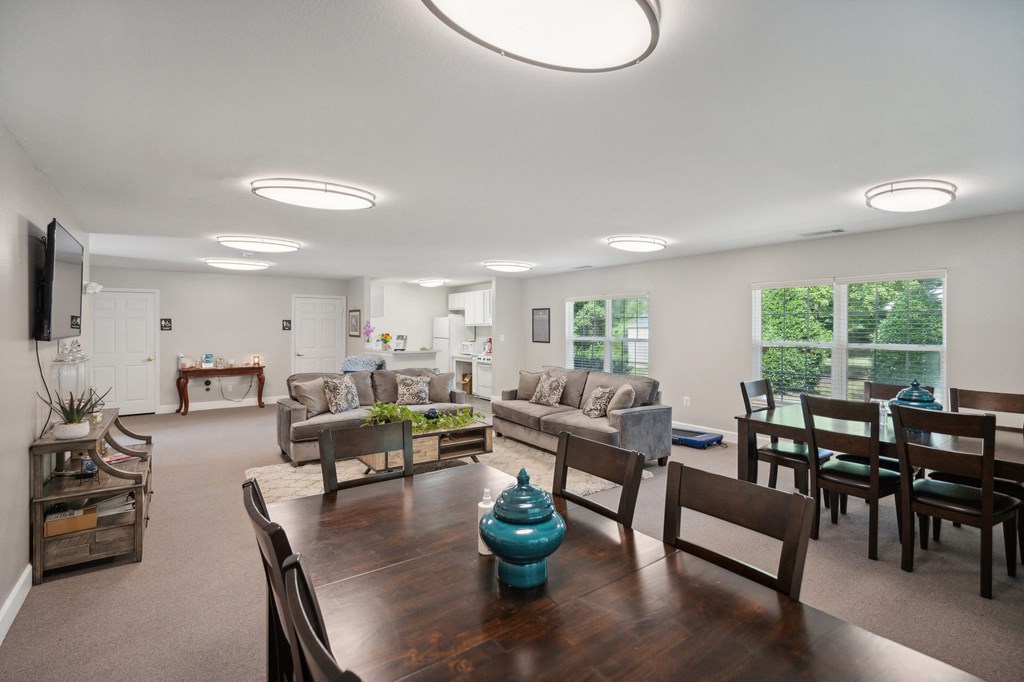 A well-lit living room with a wooden dining table and chairs.