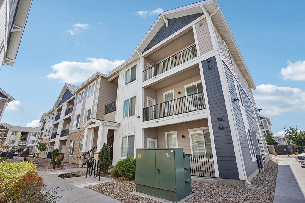 A modern apartment building with a green utility box in front. at Connect at First Creek Apartments, Denver, CO, 80249