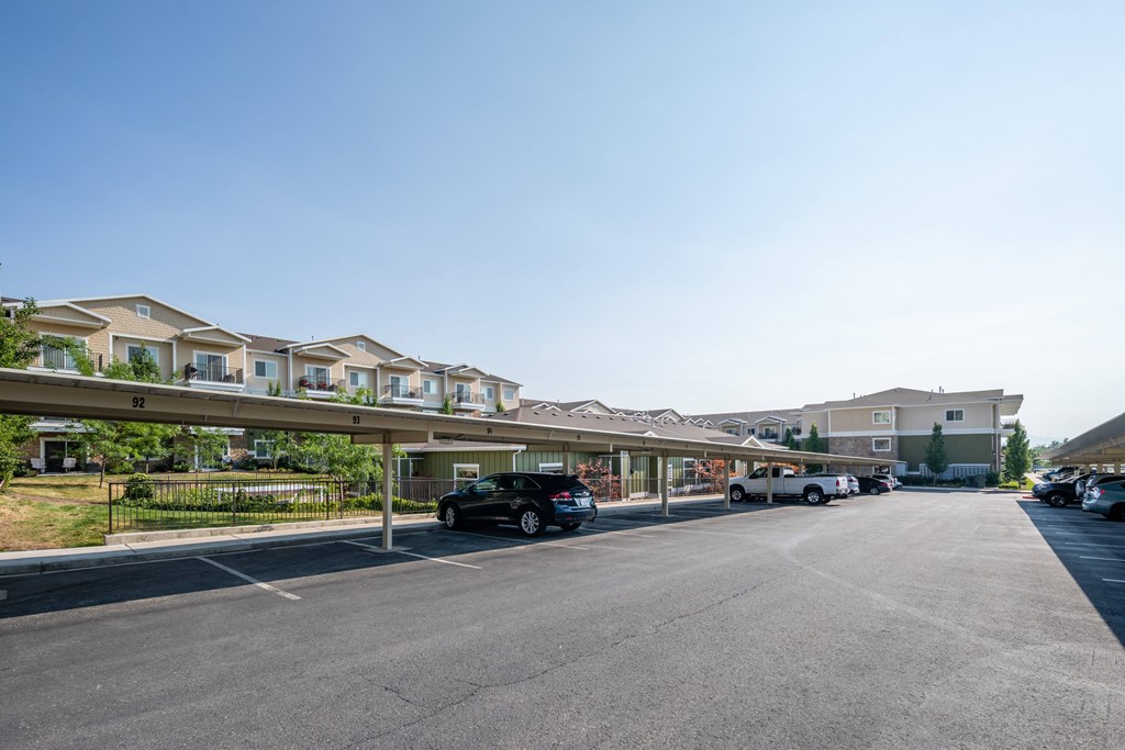 A black car is parked in a parking lot in front of a building.