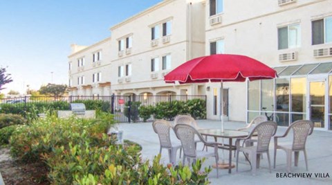 a table with a red umbrella in front of a building