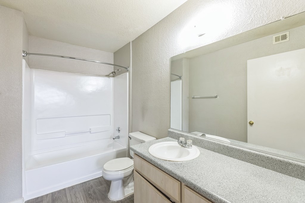 A white bathroom with a toilet, sink, and shower.