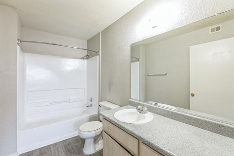 A white bathroom with a toilet, sink, and shower.