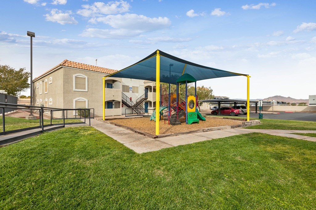 A playground with a green canopy and a yellow slide.
