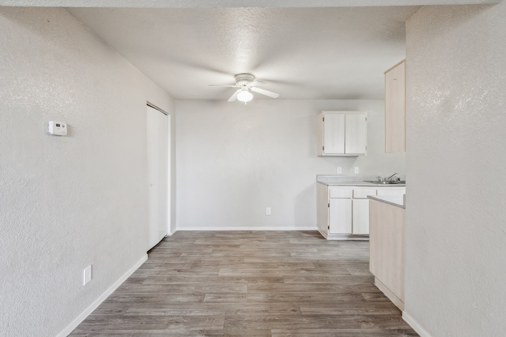 A room with a kitchenette and a ceiling fan.
