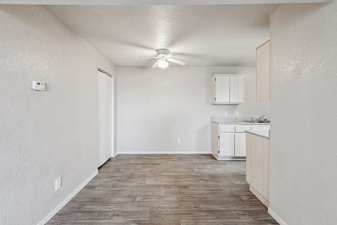 A room with a kitchenette and a ceiling fan.