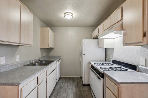 A kitchen with a white refrigerator, stove, and sink.