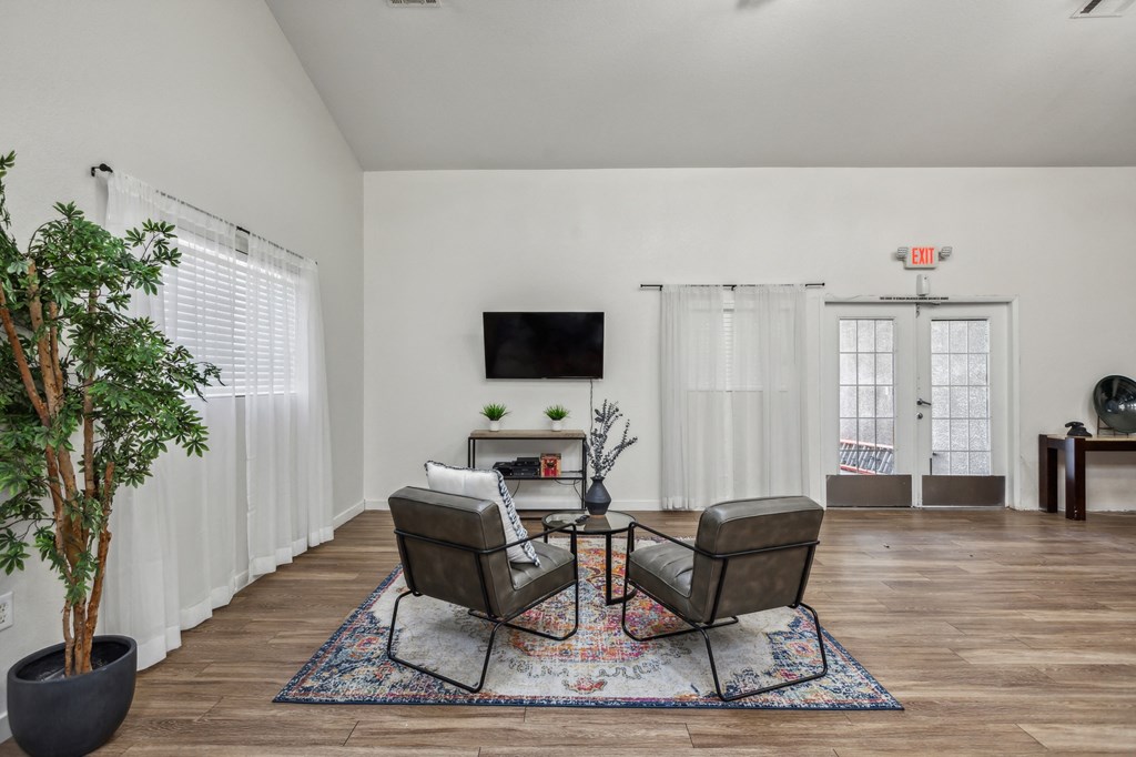 A living room with a black chair and a small table with a vase on it.