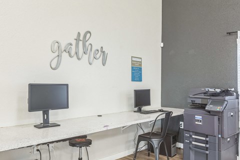 A white desk with a computer monitor and a printer on it.
