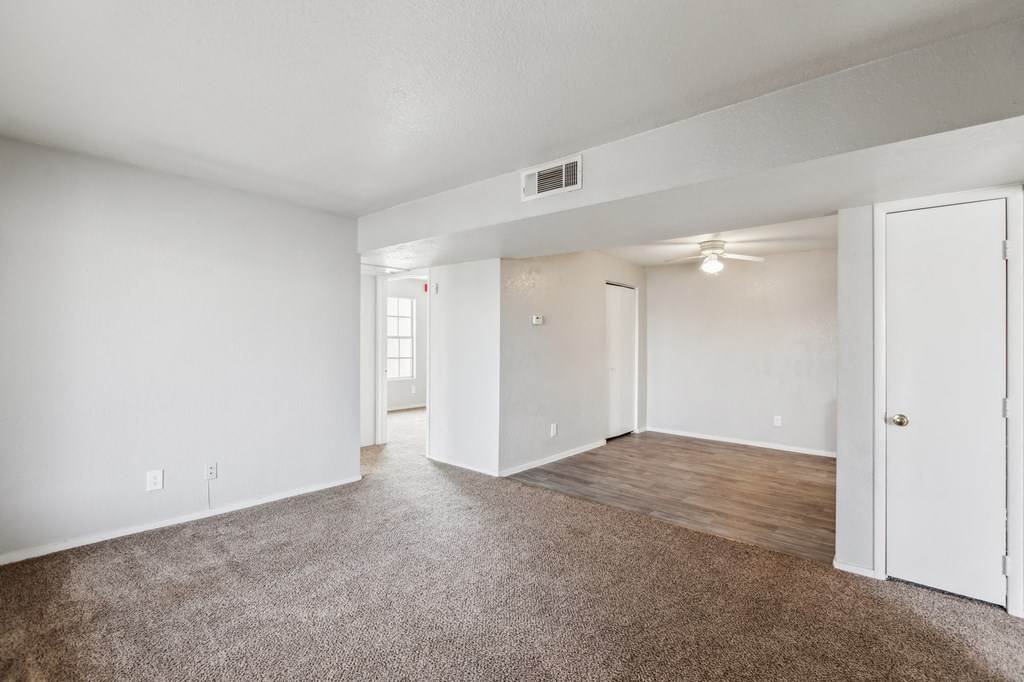 A spacious room with white walls and a brown carpet.