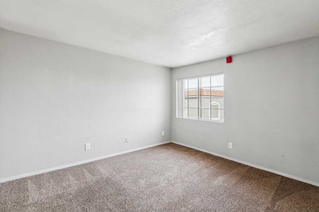A room with a window and carpeted floor.